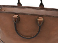 職人手作皮革兩用商務托特包 (T-7)，採用棕色皮革製成，質感溫潤。包包設有圓弧形提把，以金屬扣件固定，並飾有精緻的車縫線，展現職人細膩的工藝。