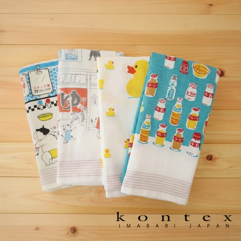 四條不同圖案的 KONTEX 日式風格吸水巾平鋪排列在淺色木紋背景上，圖案包含相撲選手與澡堂插畫、日式錢湯情境、黃色小鴨，以及各式日本瓶裝飲料圖案，展現清新質感與生活趣味。