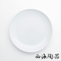 一個白色的波佐見燒 Common 陶瓷料理盤，直徑 24 公分，盤面光滑，邊緣略有弧度，底部有黑色書法字樣「西海陶器」。