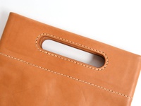 棕褐色皮革直式收納袋中袋，特寫手提把和精緻的縫線細節。