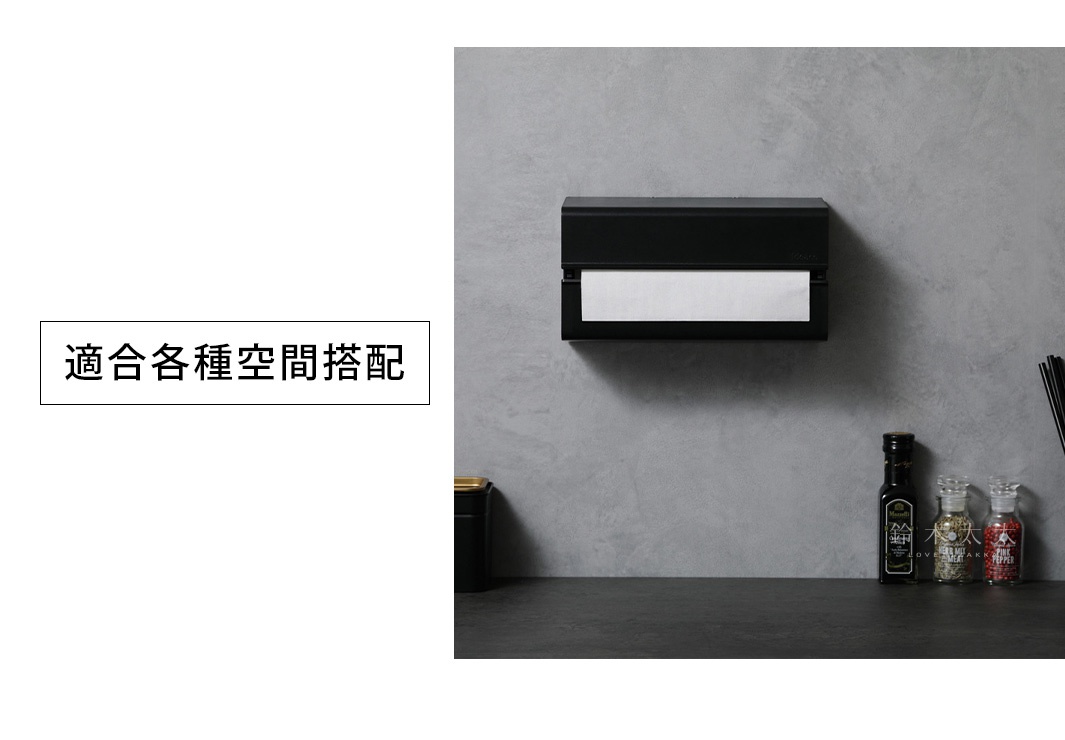 壁掛式黑色ABS擦手紙架，內含白色擦手紙，架子 mounted on a grey textured wall.