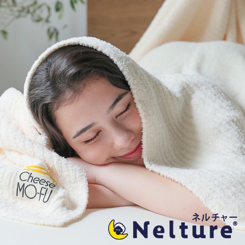 乳白色的起司風貼身舒適四季柔暖毯，質地蓬鬆柔軟，蓋在閉眼休息的年輕女性身上，毯子上印有「Cheese MO-FU」字樣的標籤。