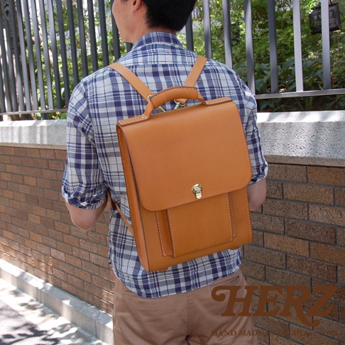 職人手作皮革復古後背包，採用光滑棕褐色皮革製成，配有金色旋轉鎖扣和外置口袋。
