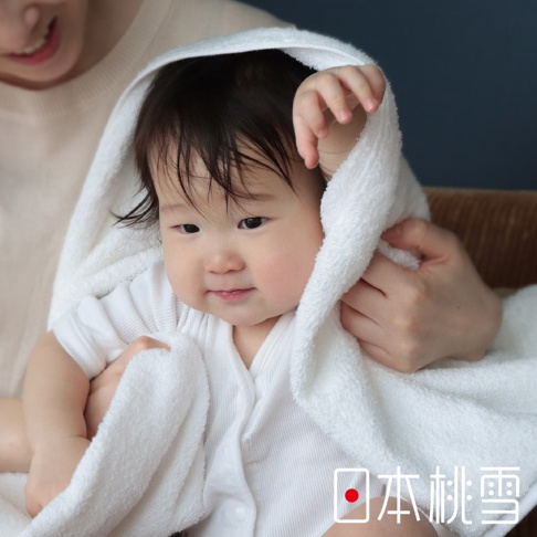 一位嬰兒被一條柔軟的白色毛巾包裹著，毛巾材質輕薄，具有良好的吸水性，適合嬰幼兒嬌嫩的肌膚。