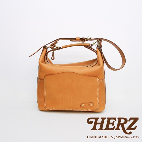 職人手作皮革厚實單肩波士頓包，呈現原色皮革質感，搭配金屬扣環與拉鍊，設計簡約實用。