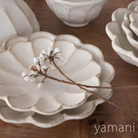 白色陶瓷主食盤，帶有花瓣狀邊緣和復古做舊質感。盤面上放著一枝帶有白色漿果的乾枯樹枝。