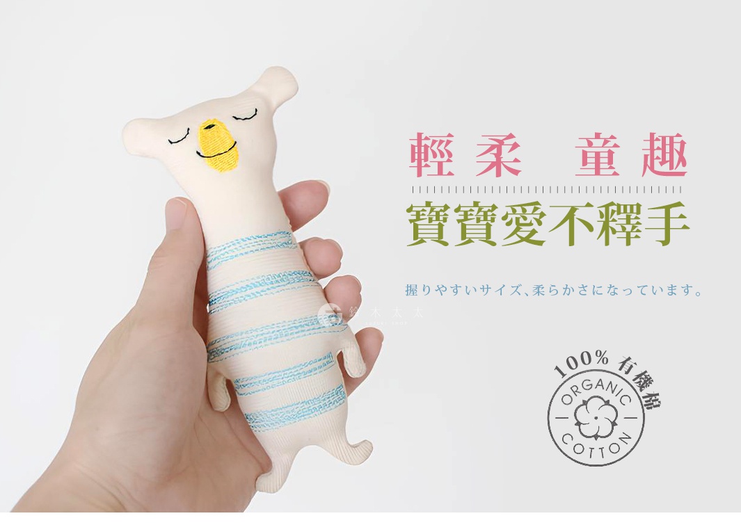手持一隻米白色、帶有藍色條紋的布偶，布偶的臉部繡有閉眼和微笑表情。