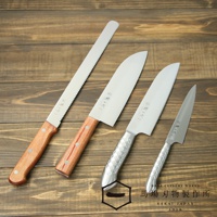 四把不鏽鋼刀具，包含鋸齒刀、兩把圓頭刀和一把尖刀，刀柄材質分別為木質和銀色金屬，刀刃上印有日文標誌。