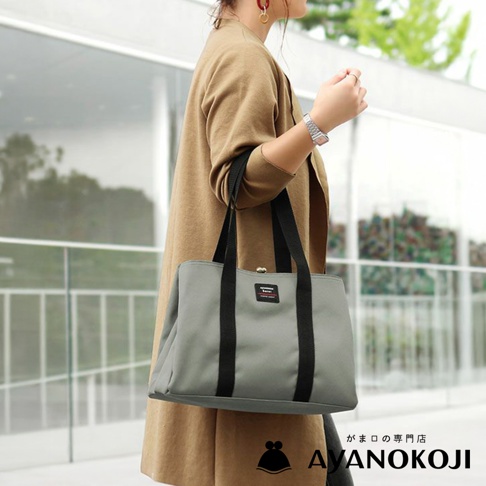 京都職人手作Sarei機能布中型口金托特包，灰色托特包搭配黑色背帶，一位女性身穿駝色外套斜背著此包款，包款左側有AYANOKOJI品牌標誌。