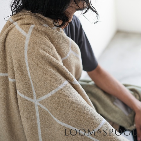 兩位人士坐著，其中一人披著一條淺棕色純棉浴巾，浴巾上印有白色幾何線條圖案。