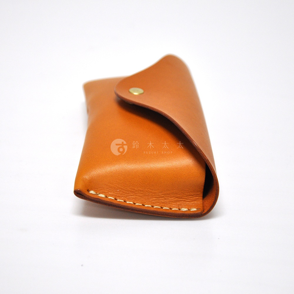 一個棕褐色的皮革眼鏡盒，採用手縫細節和金屬按扣設計，放在白色背景上。