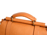 職人手作皮革屋瓦風經典雙扣後背包 (R-153) 的特寫，展示了棕褐色皮革提把、金屬環扣以及皮革包身細節。