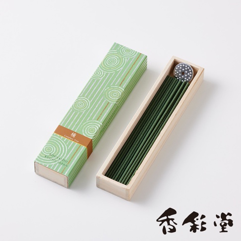 綠色紙盒裝有數支深綠色線香，盒蓋印有白色螺旋紋與細線條紋，並有褐色標籤。線香整齊擺放在淺木色木盒中，木盒內有一個圓形香灰盤。