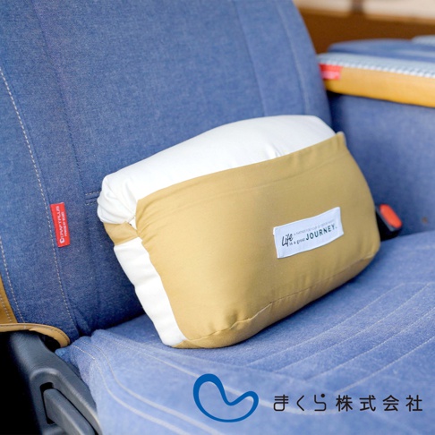 JOURNEY 旅行便攜枕，採用米白色與卡其色拼接設計，布料材質，枕套上印有「Life is a great JOURNEY.」標誌，放置於藍色車用座椅上。
