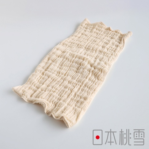 一件淺米色的褶皺紗布洗臉巾，有著荷葉邊的開口，上面印有「日本桃雪」的標誌。