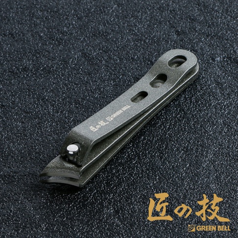 防鏽加工專足指甲剪 G-1015，採用霧面金屬材質，整體呈深灰色，設計簡潔，帶有品牌標誌「GREEN BELL」及日文「匠の技」。