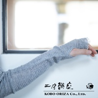 一隻手臂佩戴著淺灰色、網狀織紋的MOJIRI NECK’ｍ輕柔有機棉遮陽袖套，袖套具有指洞設計，材質輕薄透氣，邊緣有流蘇裝飾。