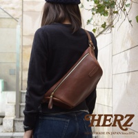 職人手作皮革輕便斜背包，棕色皮革材質，配備金色拉鍊與五金配件，斜背於身，簡約實用。