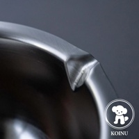 不鏽鋼料理盆的近景特寫，展示盆邊緣光滑的彎曲和一個壓出的角，材質呈現金屬光澤，背景為深灰色。