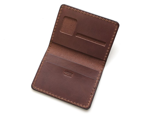 職人手作皮革雙折證件收納夾，深棕色皮革，內有證件夾層與卡片槽，邊緣縫線細緻。