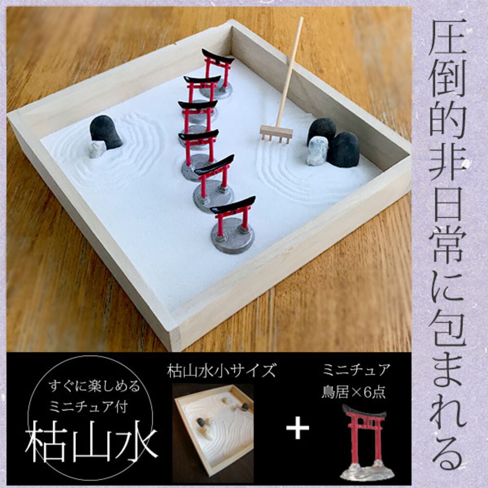 木製淺盤內盛放白色細沙，盤中錯落擺放著六個紅色鳥居模型，每個鳥居底部為灰色圓形基座。盤內另有數塊黑色鵝卵石，部分被細沙環繞。一旁插著一把迷你木製耙子，用於在細沙上耙出紋路。