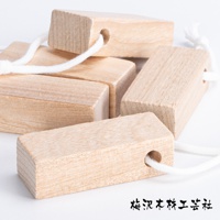 數塊天然淺棕色樟木條，每塊皆有穿孔，並穿有白色棉繩，部分木條堆疊，呈現自然紋理。