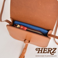 職人手作皮革流蘇側背包 CP-18，展示天然皮革的棕褐色，包內有藍色布料、黑色拉鍊零錢包，以及紅色皮革拉環。