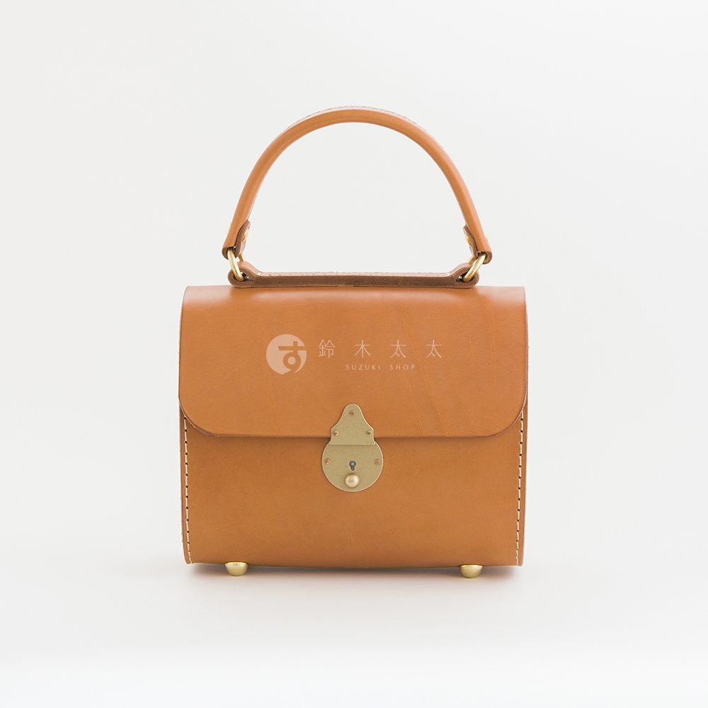 棕褐色皮革復古手提包，設有金色鎖扣和提把，底部有四個金色金屬釘，採用縫線工藝。