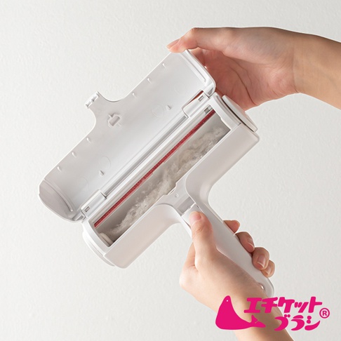 白色可水洗免耗材抗汙清潔滾輪，滾輪上帶有紅色邊緣，內含收集到的毛絮。一雙手正操作著此產品，打開滾輪上蓋。