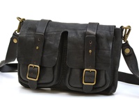 黑色皮革製成的前雙口袋肩背包，帶有兩個皮帶扣和可調節肩帶，搭配復古黃銅色五金配件。