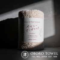 捲起的米白色有機棉浴巾，質感柔軟，上面印有日文「やさしいオーガニック」及「OBORO TOWEL」品牌字樣，標示尺寸約60x120公分，日本製造，100%純棉。