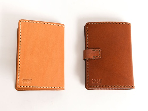 兩款職人手作皮革卡片收納夾，一款為淺棕色牛皮，另一款為深棕色牛皮，皆有清晰的縫線與品牌壓紋。