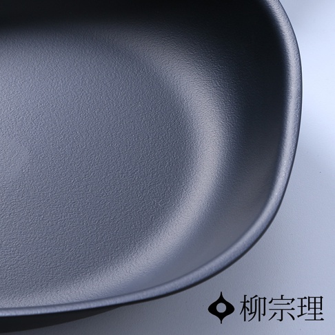 柳宗理岩紋感單手鐵鍋的內部特寫，呈現深灰色粗糙質感鍋面，右下角印有標誌性的柳宗理品牌圖示與黑色中文字樣。