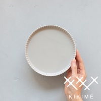 一只手拿著一個淺灰色的美濃燒高腳平盤，盤緣帶有放射狀的紋理。