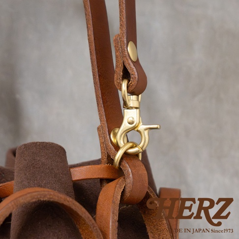 HERZ 職人手作皮革的質感細節，特別是黃銅金屬釦環與棕色皮革的精緻連接處