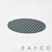 深灰色矽膠隔熱墊，表面有規則的波浪紋路，邊緣呈鋸齒狀，橢圓形設計。