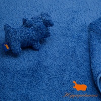 藍色竹棉混紡厚浴巾，質地柔軟，表面有毛圈紋理。左側有一隻藍色河馬造型的毛巾掛飾，掛飾上縫有橘色品牌標籤。右側可見浴巾邊緣及一條藍色綁繩。