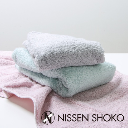 粉紅色、薄荷綠色和淺灰色三條毛巾堆疊，材質為柔軟的毛巾布料，背景為白色。