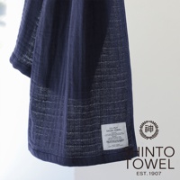 深藍色2.5層紗浴巾，材質輕薄透氣，表面有細緻的紋理，左下角有產品標籤及品牌Logo。