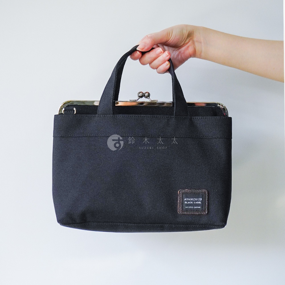 手提黑色手提包，上面有金色金屬扣。