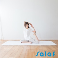 一位身穿白色上衣和灰色長褲的亞洲女性，正在一個白色的 SALAF 涼感睡墊上練習瑜珈。她以單腿盤坐的姿勢，將一隻腳彎曲至身後，並用同側的手抓住腳踝，身體向後仰，展現優美的體態。