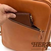 職人手作皮革長方型多口袋後背包，展示棕色皮革外層，一個拉鍊口袋內可見一個深棕色皮革錢包，金屬拉鍊和縫線清晰可見。