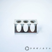 銀色金屬製試管架，可容納三個試管，頂部有三個圓形開口，下方有三個橢圓形開口。