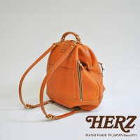 職人手作皮革輕旅行後背包，採用溫暖的橘棕色皮革，搭配米白色縫線。包款設計簡約，側面有一個拉鍊口袋，雙肩帶可調節。