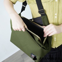 一名女子身穿格紋上衣，身背綠色方形口金包，手正打開包包。