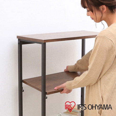 寬型四層層架，木紋層板搭配黑色金屬框架，一位身穿米色毛衣的女性正在調整其中一層層板。