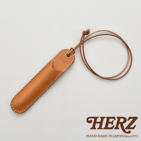 職人手作皮革掛繩筆套，附有品牌標誌和製造地說明。