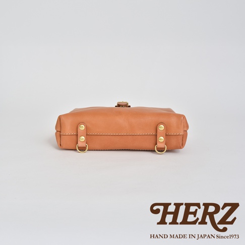 職人手作皮革迷你軟皮杜勒斯包，採用淺棕色柔軟皮革，搭配金色金屬扣環和铆釘，包身線條簡潔，展現職人手工質感。