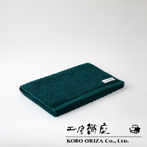 ECOR 天然系人字紋有機棉毛巾，深綠色，觸感柔軟，織有經典人字紋理，邊緣有品牌標籤。