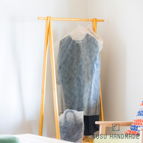 檜木薰衣草香氛衣物防塵套 L，半透明材質，用於保護掛在淺木色衣架上的深色衣物及一個黑色手提袋。